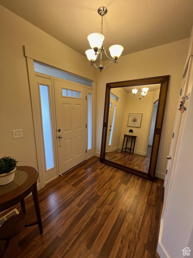 foyer entrance featuring an inviting chandelier, baseboards, and dark wood-type flooring