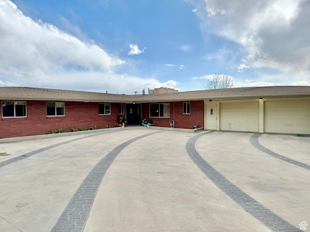 ranch-style house featuring concrete driveway, brick siding, and a garage