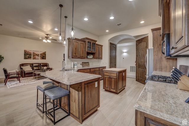 595 W 2050 S, Hurricane, UT 84737 - kitchen featuring a breakfast bar area, a sink, light wood-style floors, arched walkways, and a peninsula