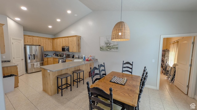 kitchen featuring light tile patterned floors, light brown cabinets, stainless steel appliances, a kitchen bar, and a peninsula