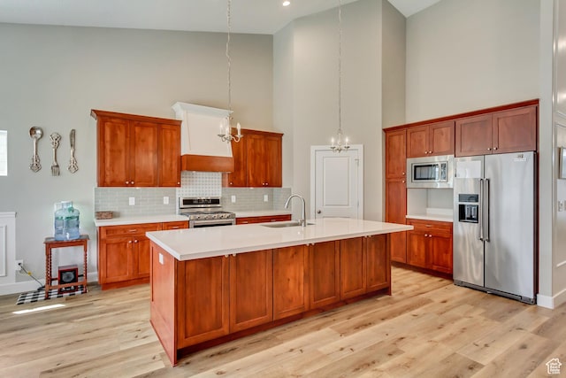 kitchen featuring a sink, appliances with stainless steel finishes, light countertops, an inviting chandelier, and high vaulted ceiling