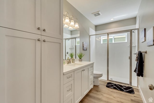 full bathroom featuring a shower stall, visible vents, toilet, wood finished floors, and vanity