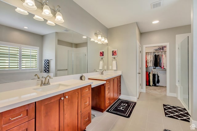 bathroom featuring a spacious closet, vanity, baseboards, visible vents, and a stall shower