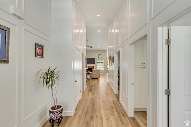 hallway with recessed lighting, light wood-style flooring, and a decorative wall