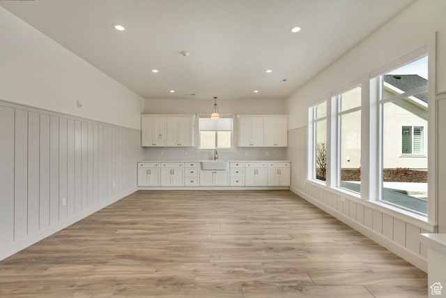 interior space with recessed lighting, light countertops, a sink, white cabinetry, and light wood-type flooring