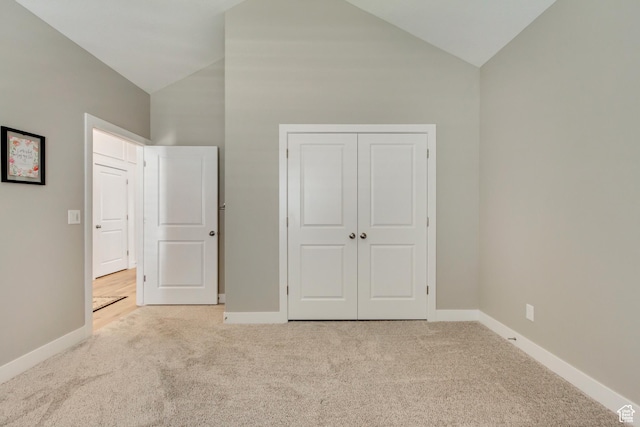 unfurnished bedroom featuring a closet, carpet flooring, high vaulted ceiling, and baseboards
