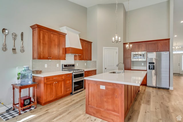 kitchen featuring a sink, stainless steel appliances, a notable chandelier, high vaulted ceiling, and light wood-style flooring