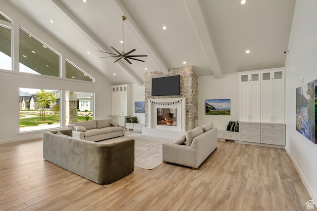 living room featuring beamed ceiling, light wood-style floors, high vaulted ceiling, a multi sided fireplace, and a ceiling fan