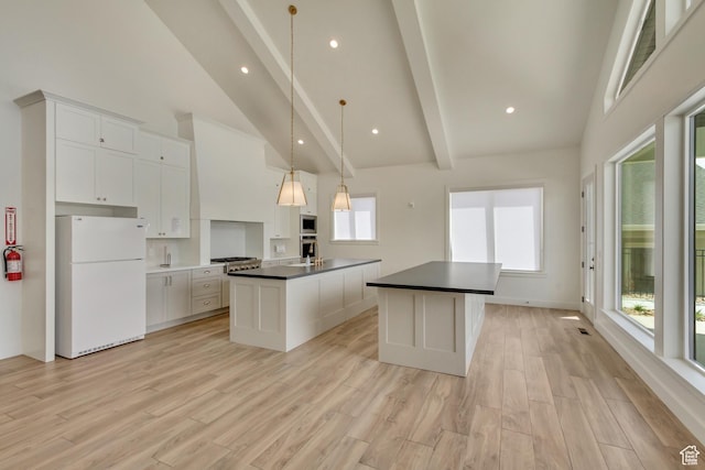 kitchen featuring a kitchen island with sink, freestanding refrigerator, beamed ceiling, dark countertops, and high vaulted ceiling