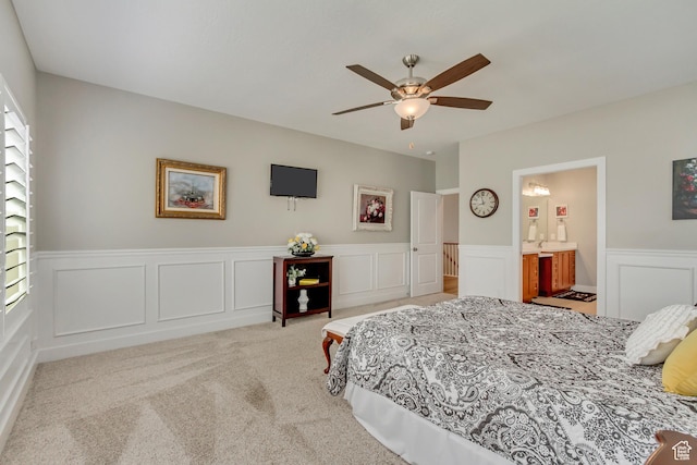 carpeted bedroom featuring a decorative wall, a wainscoted wall, ceiling fan, and connected bathroom