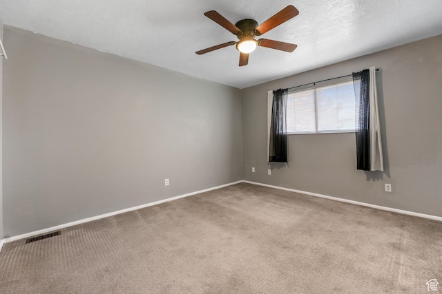 carpeted spare room featuring a ceiling fan and baseboards