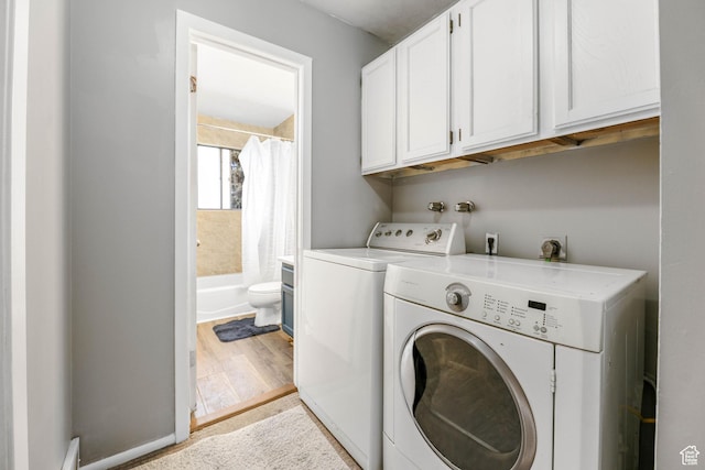 laundry room with cabinet space, separate washer and dryer, and wood finished floors