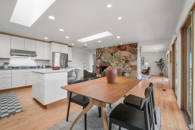 813 N Northview Dr E, Salt Lake City, UT 84103 - dining room with recessed lighting, a skylight, a stone fireplace, and light wood-style flooring