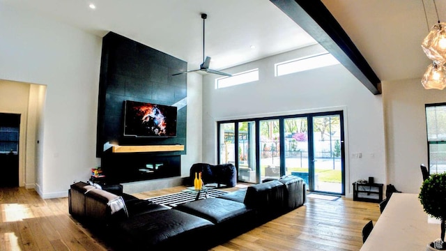 13327 S Bullitt Ln, Draper, UT 84020 - living area featuring light wood-style floors, a fireplace, baseboards, a ceiling fan, and a towering ceiling
