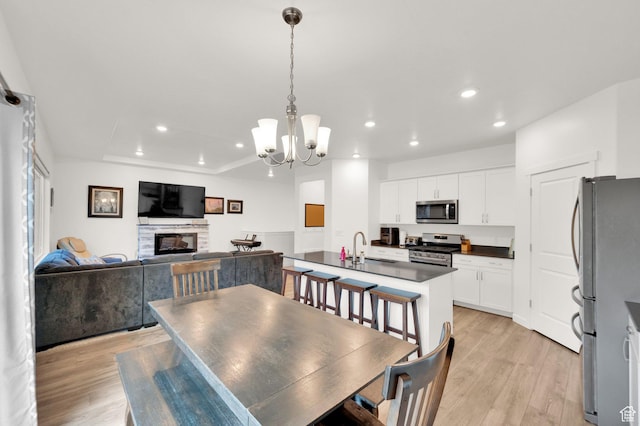 1131 S Red Cliff Dr, Santaquin, UT 84655 - dining space featuring a fireplace, light wood finished floors, recessed lighting, and a notable chandelier