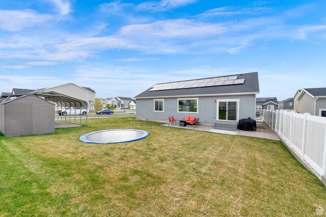 1131 S Red Cliff Dr, Santaquin, UT 84655 - back of property featuring a lawn, a carport, a fenced backyard, roof mounted solar panels, and entry steps