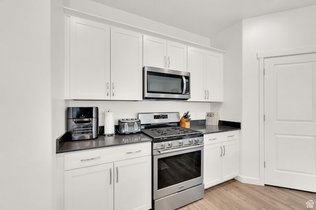 1131 S Red Cliff Dr, Santaquin, UT 84655 - kitchen with stainless steel appliances, dark countertops, white cabinetry, and light wood-style flooring