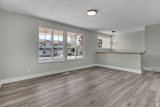 3502 W 8350 S, West Jordan, UT 84088 - spare room with a textured ceiling, visible vents, wood finished floors, and a chandelier