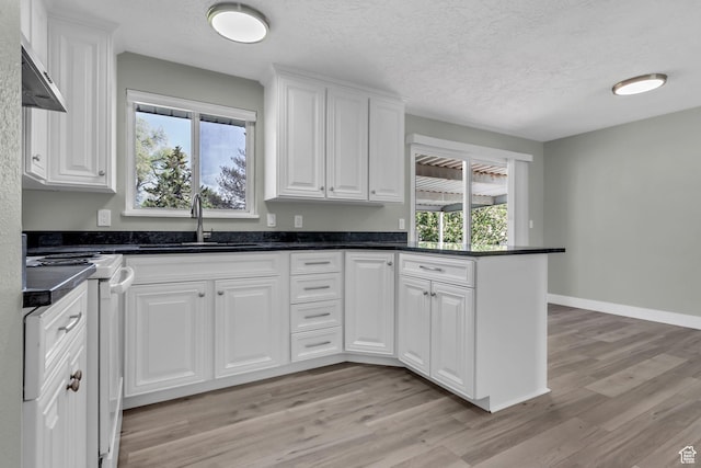 3502 W 8350 S, West Jordan, UT 84088 - kitchen with white cabinets, range, a sink, light wood-style floors, and a peninsula