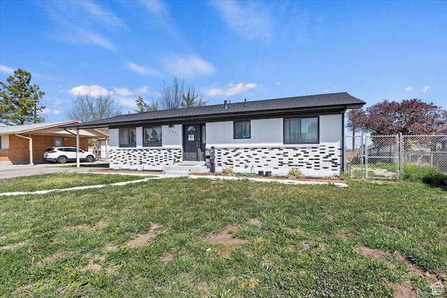 view of front of home with brick siding, fence, a carport, and a front lawn