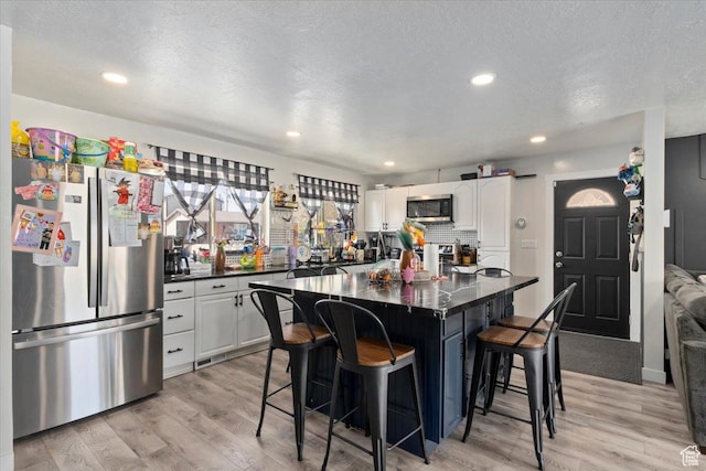 3902 W 4955 S, Taylorsville, UT 84129 - kitchen with appliances with stainless steel finishes, dark countertops, a kitchen bar, and white cabinetry