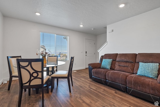 dining space with a textured ceiling, dark wood-style flooring, and baseboards
