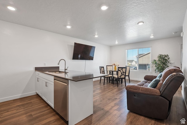 kitchen with a sink, a peninsula, dark countertops, dishwasher, and open floor plan