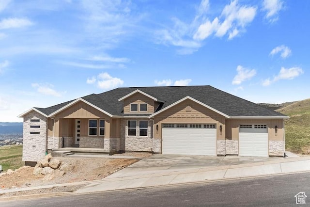 view of front of property with driveway, a garage, a porch, and stone siding