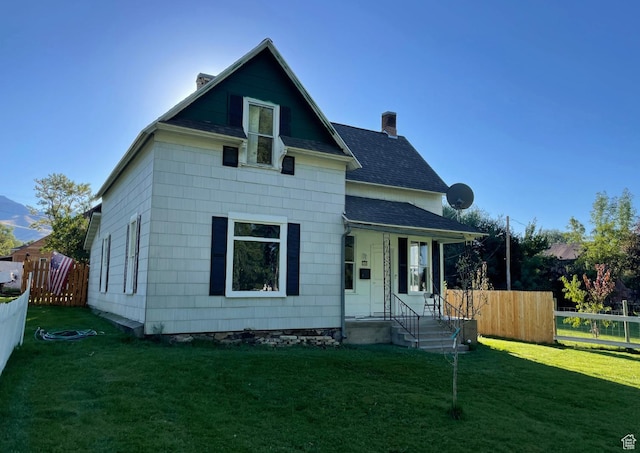bungalow-style house with a chimney, fence, a shingled roof, and a front lawn