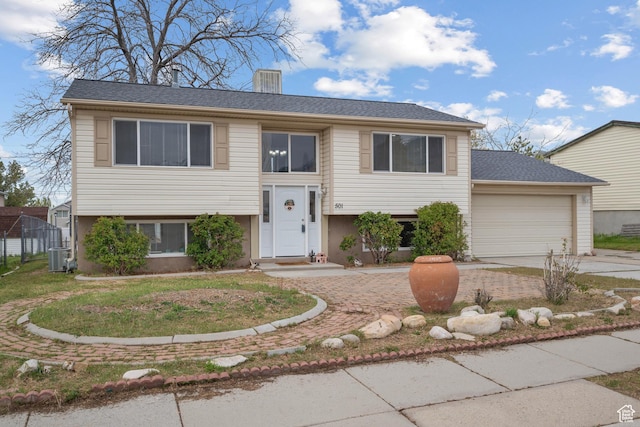 501 Valley View Dr, Tooele, UT 84074 - split foyer home featuring a garage, a chimney, concrete driveway, and central air condition unit