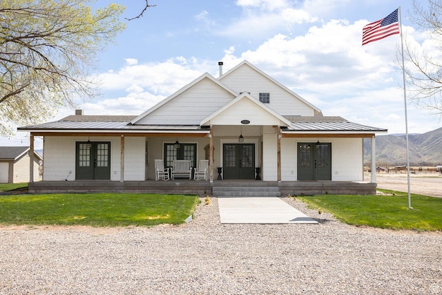 modern farmhouse with a porch, a standing seam roof, metal roof, a mountain view, and french doors