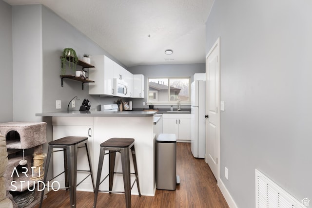 1004 N 1090 W Unit 401, Orem, UT 84057 - kitchen with white appliances, a sink, a peninsula, dark wood finished floors, and a breakfast bar