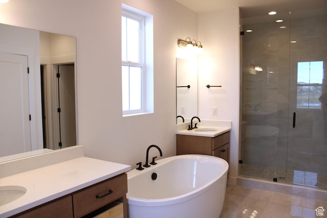 bathroom featuring a shower stall, a sink, two vanities, a freestanding bath, and tile patterned flooring