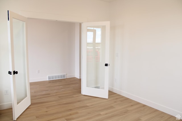 unfurnished room with visible vents, baseboards, french doors, and light wood-style floors