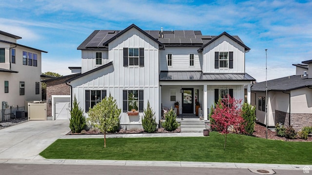 modern farmhouse with a standing seam roof, covered porch, a front yard, and board and batten siding