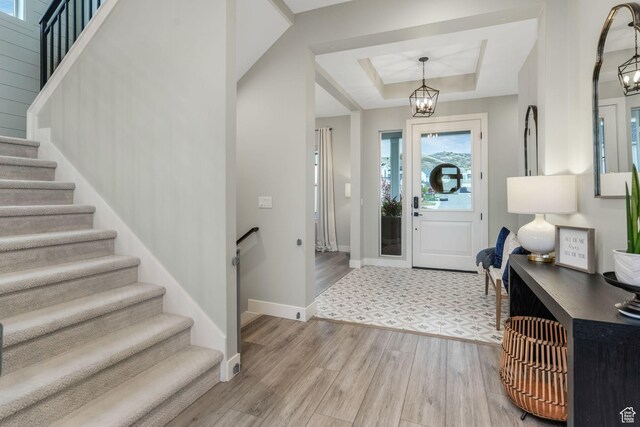 4772 W Thorntree Ln, Herriman, UT 84096 - entrance foyer featuring stairs, light wood-style flooring, baseboards, a raised ceiling, and a notable chandelier