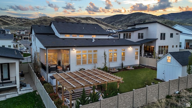 4772 W Thorntree Ln, Herriman, UT 84096 - back of house at dusk with a mountain view, a fenced backyard, a shed, and an outdoor structure