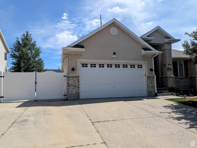 846 E 2200 S, Clearfield, UT 84015 - view of front facade featuring a gate, driveway, a garage, stone siding, and stucco siding