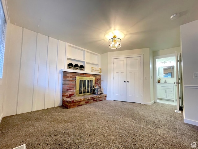 unfurnished living room featuring a brick fireplace, a sink, carpet floors, and baseboards