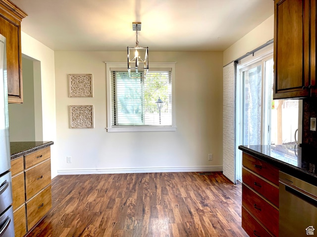 unfurnished dining area with baseboards, a chandelier, and dark wood finished floors