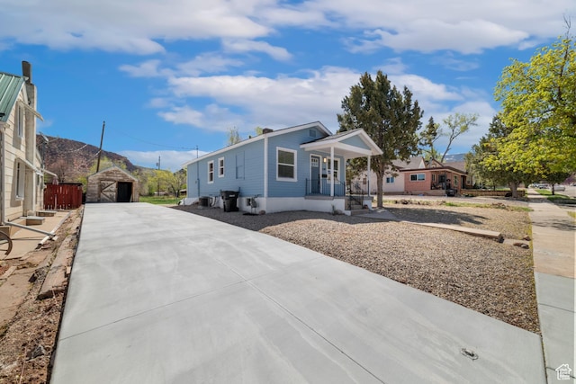 view of front of home with driveway, an outdoor structure, a detached garage, a mountain view, and a porch