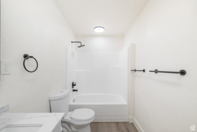 bathroom featuring vanity, toilet, baseboards, tub / shower combination, and wood finished floors