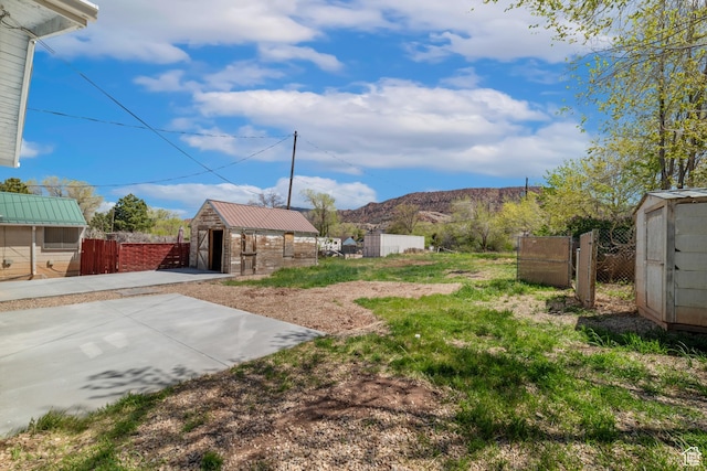view of yard featuring a garage, a mountain view, fence, and an outdoor structure