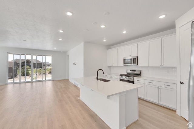 4099 W 2025 S Unit 51, Taylor, UT 84401 - kitchen featuring appliances with stainless steel finishes, a kitchen island with sink, recessed lighting, light wood-style flooring, and white cabinets