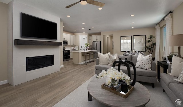 4099 W 2025 S Unit 51, Taylor, UT 84401 - living area with light wood finished floors, a ceiling fan, recessed lighting, baseboards, and a tile fireplace