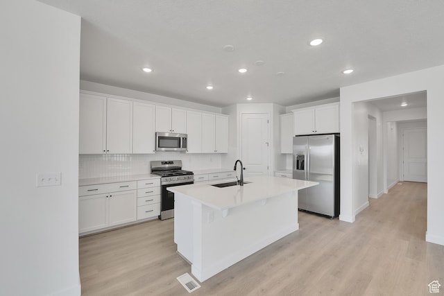 4099 W 2025 S Unit 51, Taylor, UT 84401 - kitchen with appliances with stainless steel finishes, light wood-type flooring, an island with sink, white cabinetry, and tasteful backsplash