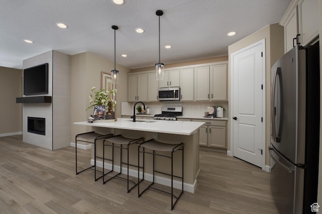 4099 W 2025 S Unit 51, Taylor, UT 84401 - kitchen with appliances with stainless steel finishes, a sink, tasteful backsplash, a kitchen breakfast bar, and light wood-style flooring