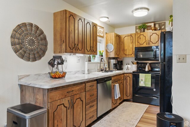 687 W Le Bon Cir, Provo, UT 84601 - kitchen with a sink, light wood-style floors, light countertops, black appliances, and brown cabinetry