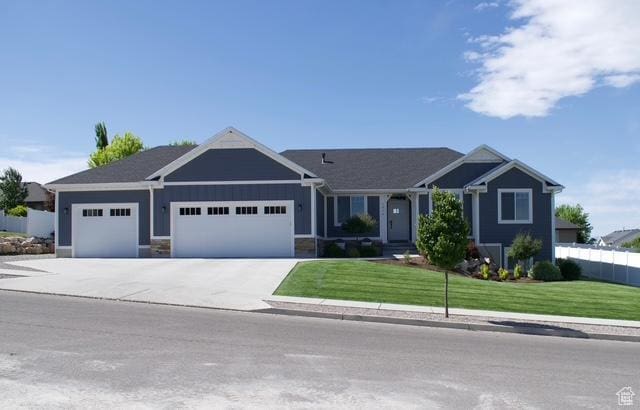 view of front of property with driveway, fence, a front lawn, and a garage