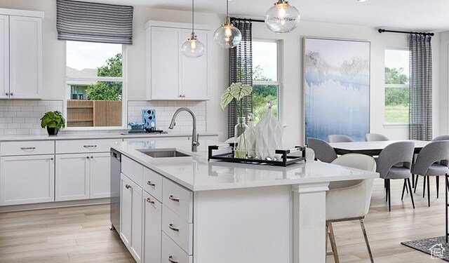 2074 S 3940 W Unit 11, Taylor, UT 84401 - kitchen featuring a sink, a center island with sink, light wood finished floors, and tasteful backsplash